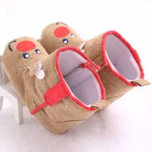 Close-up of warm brown baby booties with red trim and cute reindeer character design