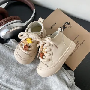 Detailed view of cream toddler sneakers with chunky rope laces and letter beads