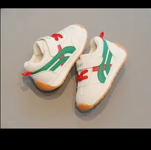 Dettaglio di scarpe da ginnastica bianche per bambini con strisce verdi e lacci rossi