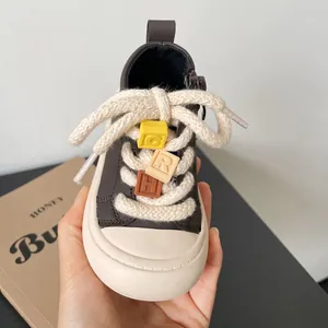 Close-up of toddler soft sole walking shoe with colorful letter charms and thick rope laces.