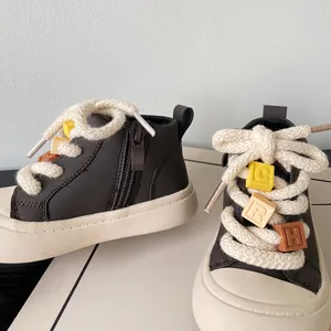 Detail of brown children's boots featuring a side zipper and letter block laces.