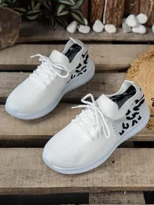 Ademende witte gebreide damessneakers met zwarte luipaardprint op houten pallets