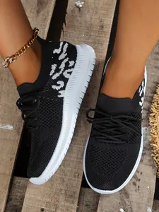 Close-up van zwarte gebreide sneakers met wit patroon op houten achtergrond