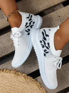 Gedetailleerd zijaanzicht van witte fly-knit sneakers voor dames met luipaardprint