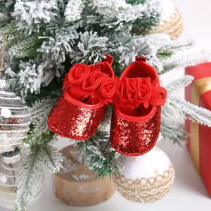 Close-up of red glittery baby princess shoes with floral details on a Christmas tree