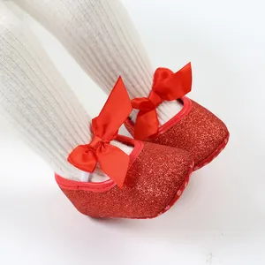 Detail view of red glittery baby princess shoes with decorative bows and soft soles for Christmas.