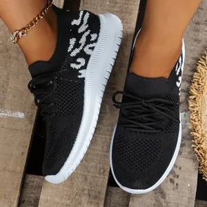 Detailopname van zwarte fly-knit platform sneakers voor dames op houten bodem