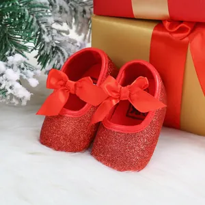 Close-up detail of sparkling red glitter baby princess shoes with large satin bows.