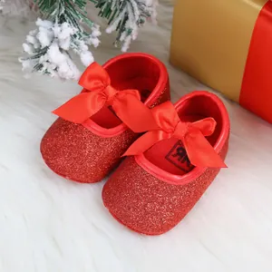 Macro view of sparkly red baby princess shoes with a festive Christmas gift backdrop