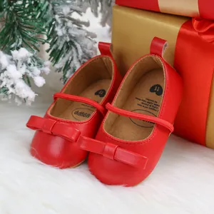 Close-up of red baby princess shoes with a bow for Christmas on a white fur background.