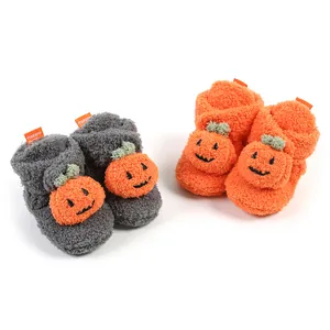 Dettaglio di scarpine per neonati in peluche con simpatico design a zucca arancione.