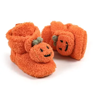 Dettaglio di babbucce invernali in peluche arancione per neonati con zucca ricamata
