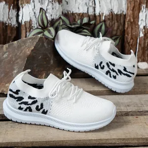 Detailopname van witte fly-knit hardloopschoenen voor dames met panterprint en dikke zolen