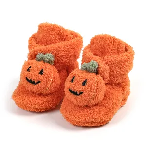 Dettaglio di scarpine invernali per neonati a tema zucca in morbido pile arancione caldo