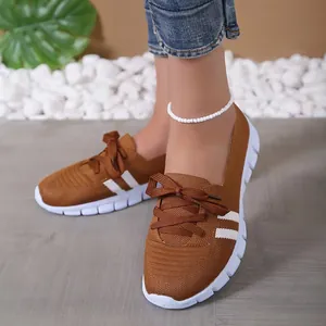 Detailed view of breathable brown fly-knit sneakers on model walking on a wooden floor