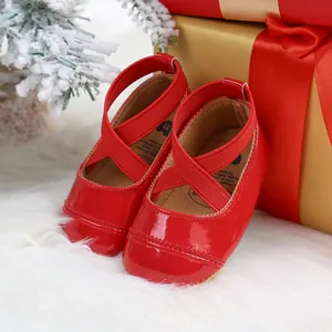 Festive red patent leather baby princess shoes with cross straps in Christmas setting