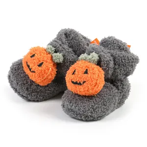 Primo piano della decorazione a zucca su morbidi stivaletti invernali grigi in peluche per neonati