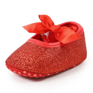 Detailed close-up view of red glitter infant princess shoe with a red satin bow