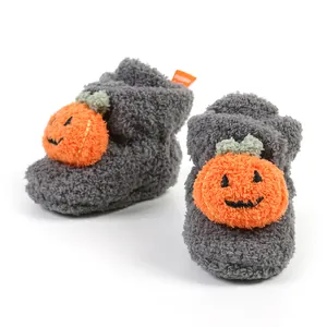 Dettaglio ravvicinato della morbida texture e del design a zucca sulle babbucce grigie neonato.