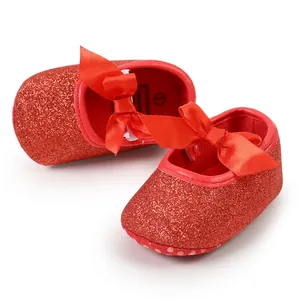 Detailed macro shot of sparkly red baby shoes with an elegant soft satin bow