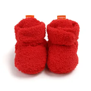 Dettaglio ravvicinato di stivaletti invernali in peluche rosso per neonati con texture