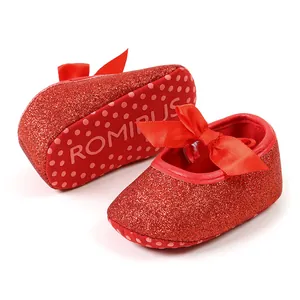 Detailed macro view of red glitter baby princess shoes with satin bow and soft sole
