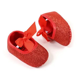 Macro view of red glitter baby princess shoes with a silk bow and soft sole detail
