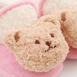 Detailed macro view of a cute plush bear on soft pink fleece baby walking shoes.