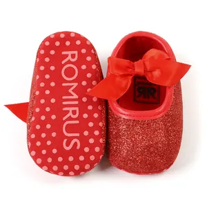 Detail of red glittery baby princess shoes with satin bow and non-slip sole.