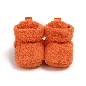Primo piano di scarpine invernali per neonati in morbido pile arancione dalla grana fine