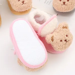 Detail of soft-soled pink baby booties with non-slip grip and cute bear decoration.