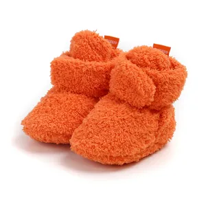 Vista ravvicinata di scarpine invernali per neonati in morbido pile arancione brillante