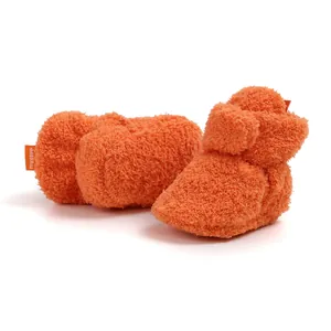 Primo piano di stivaletti per bambini in peluche arancione per il calore durante l'inverno