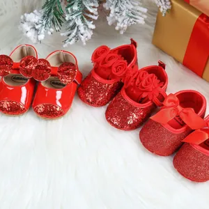 Festive red baby princess shoes with glitter and bows presented on white fur background