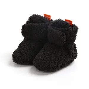 Primo piano di scarpine invernali in pile nero per neonati con morbida trama soffice