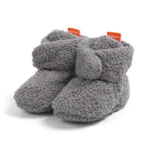Dettaglio di accoglienti scarpine invernali in pile grigio per neonati con fodera calda