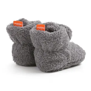 Primo piano dettagliato di scarpe da neonato in pile grigio spesso con piccola etichetta arancione