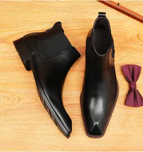 Vista superior de botas Chelsea de cuero negro para hombre con una elegante pajarita