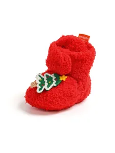 Dettaglio di scarpina neonato in peluche rossa con ricamo festivo di albero di Natale