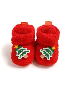 Dettaglio di scarpine in peluche rosso per neonati con ricamo a forma di albero