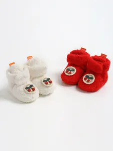 Dettaglio di scarpine invernali in peluche rosse e bianche con simpatico motivo ciliegia