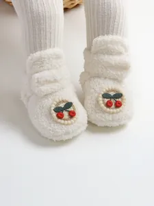 Dettaglio di stivaletti invernali in peluche per neonati con ricamo a ciliegia su bianco