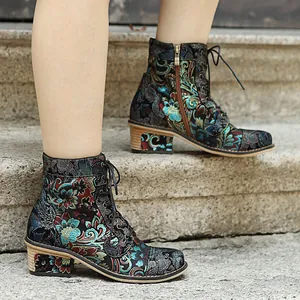 Detailed side view of vintage floral embroidered ankle boots for women on stone steps