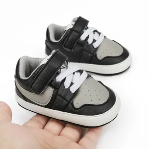 Detail view of stylish black and grey infant walking shoes held in hand for scale