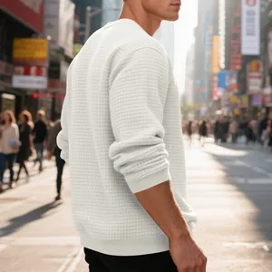 Detail of men's white waffle knit sweatshirt with square pattern and ribbed cuffs.