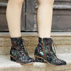 Detail view of vintage ethnic floral lace-up ankle boots worn on stone steps