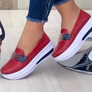 Detail view of stylish women's red platform loafers featuring white soles and buckle decor