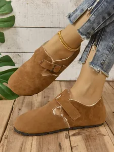 Primer plano de mocasines de ante marrón con forro de felpa y detalle de hebilla