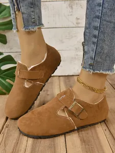 Primer plano de mocasines de ante marrón para mujer con forro de piel y detalle de hebilla