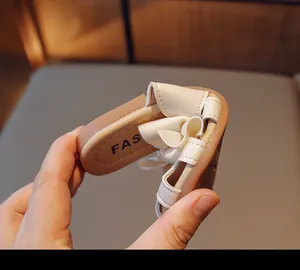 Close-up showing the extreme flexibility and soft material of the white bow toddler sandal